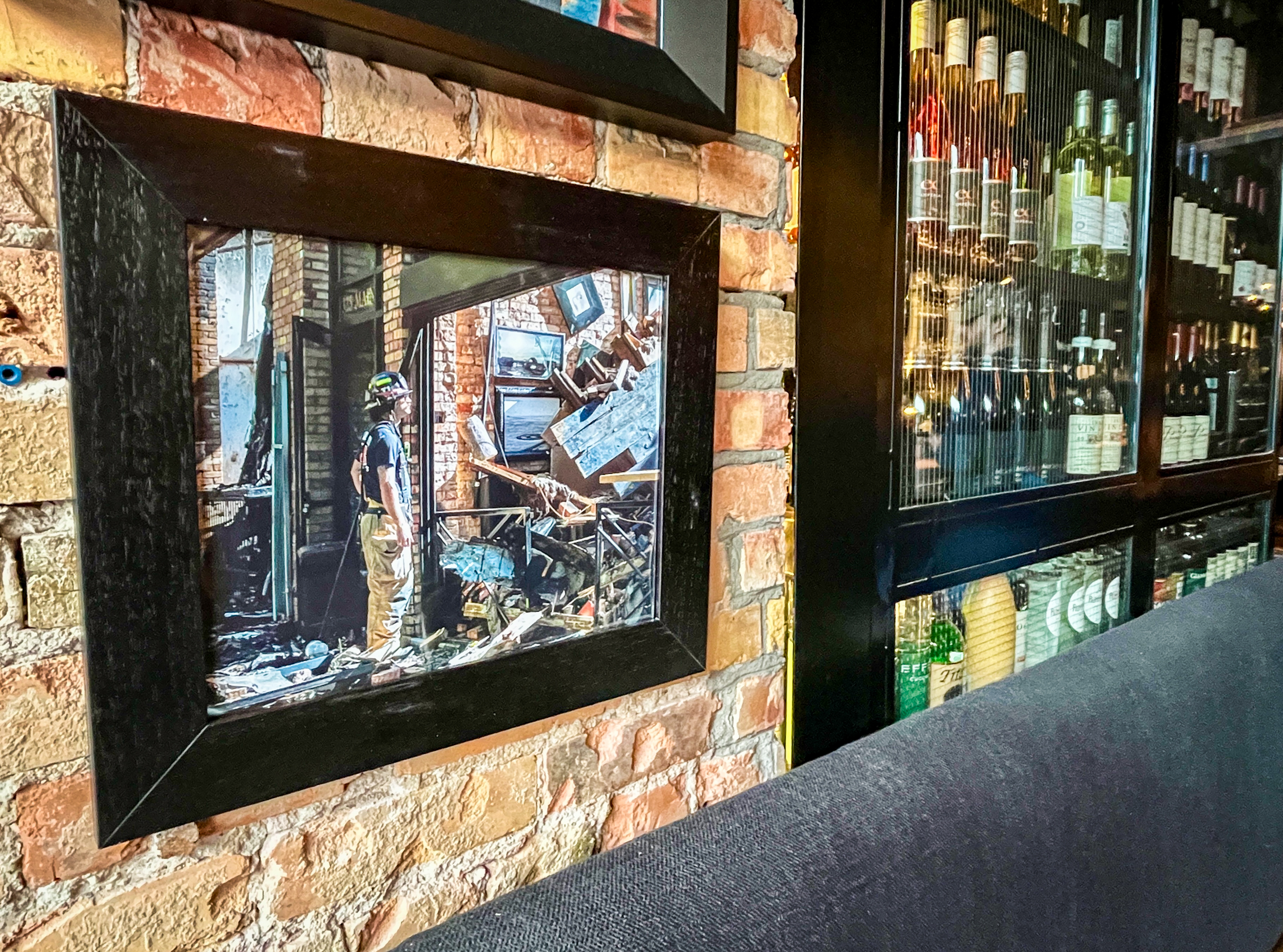 A photo of a firefighter inspecting damage at White Horse Spirits & Kitchen last year hangs on the wall of the restaurant on Thursday. The fire heavily damaged the business.