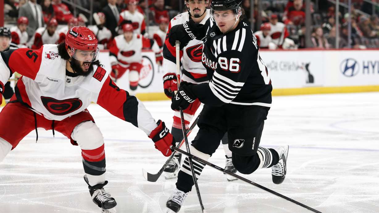 New Jersey Devils center Jack Hughes (86) has his shot knocked away by Carolina Hurricanes defenseman Jalen Chatfield (5) during the second period of an NHL hockey game Saturday, Jan. 17, 2026, in Newark, N.J.