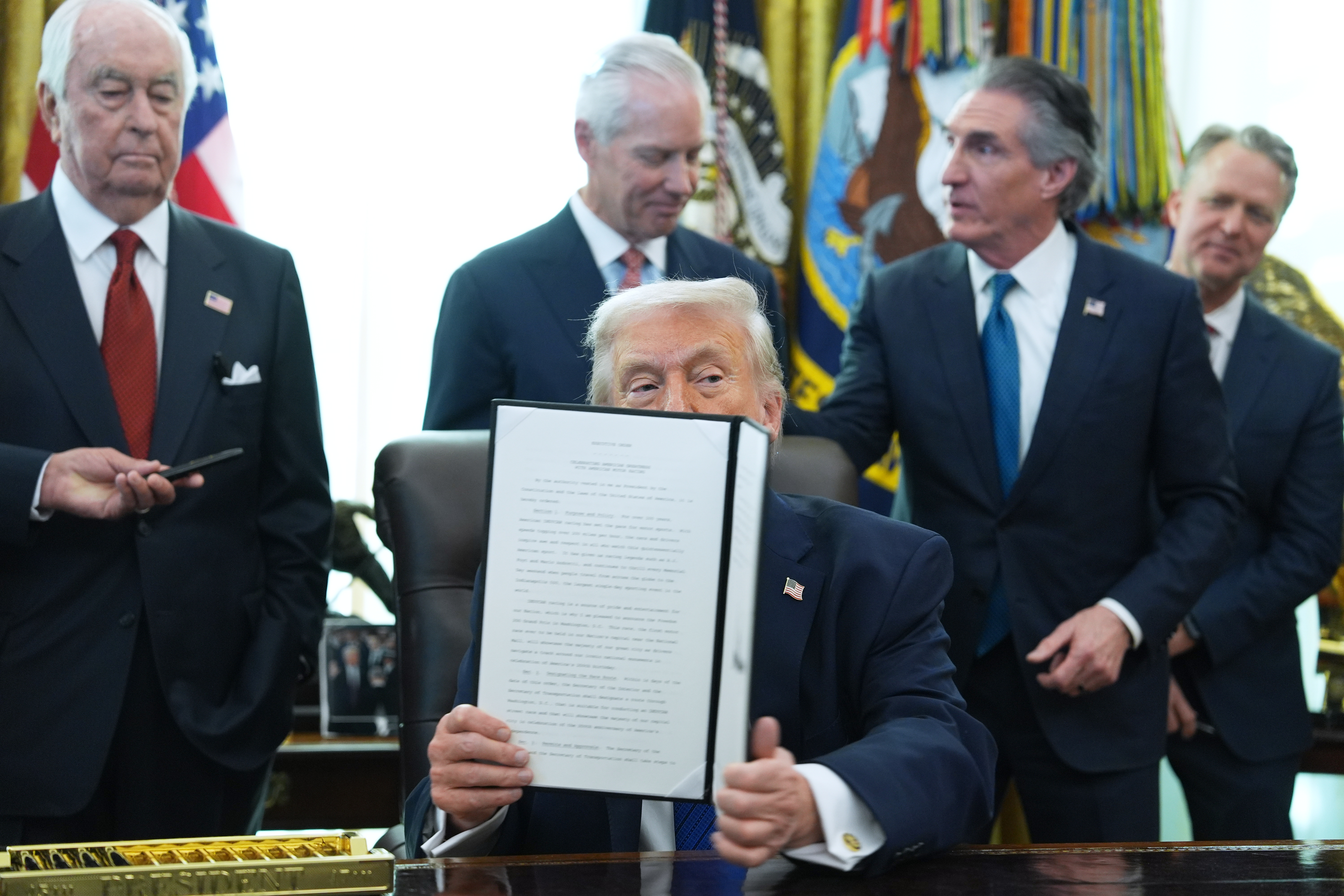 President Donald Trump holds an executive order he signed in the Oval Office of the White House, Friday, Jan. 30, 2026, in Washington. 