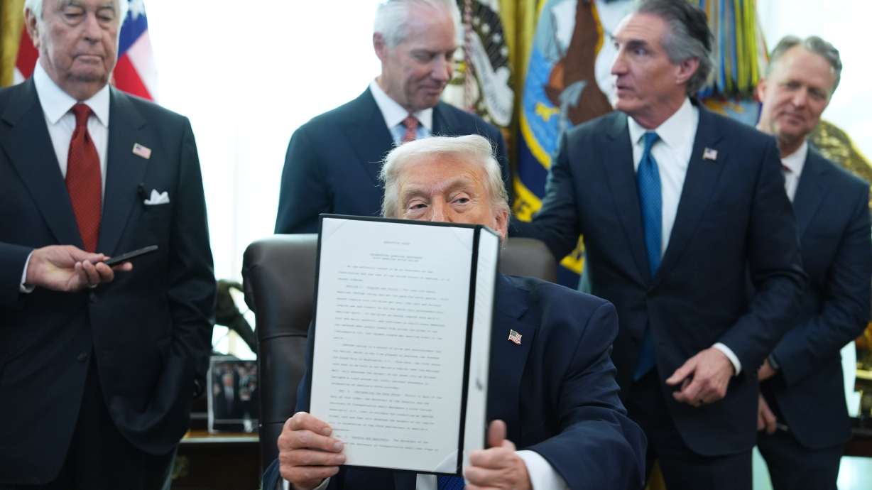 President Donald Trump holds an executive order he signed in the Oval Office of the White House, Friday, Jan. 30, 2026, in Washington.
