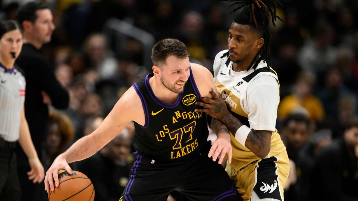 Los Angeles Lakers guard Luka Doncic (77) dribbles against Washington Wizards guard Jamir Watkins, right, during the first half of an NBA basketball game, Friday, Jan. 30, 2026, in Washington.