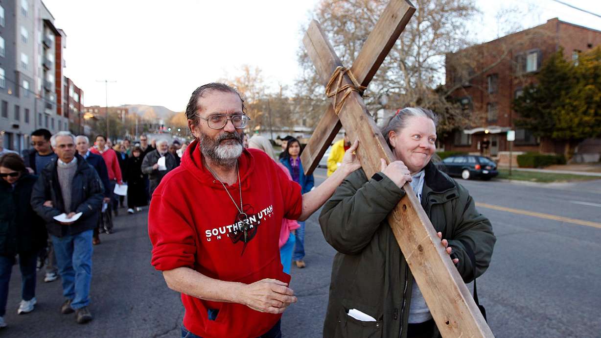 Alex Bury passes off a cross to Patty Bury as a Good Friday Cross Procession moves through downtown Salt lake City, April 3, 2015.
