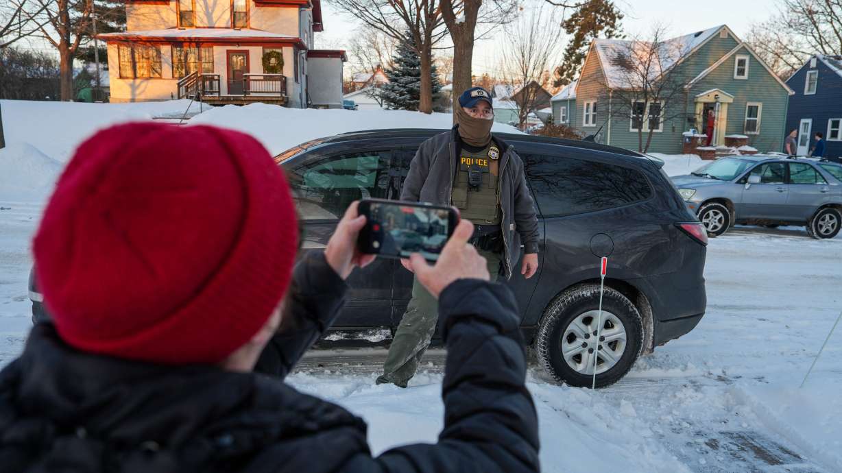 Activists confront a federal agent while conducting immigration enforcement operations in a neighborhood on Monday in Minneapolis.