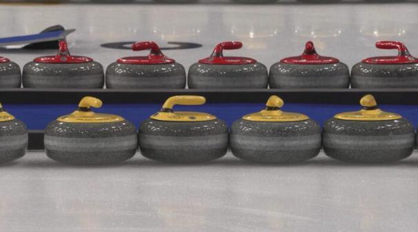 Stones sit inside the Cortina Curling Olympic Stadium.
