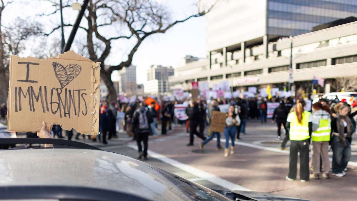 The driver of a car holds a sign as anti-ICE protesters march past in Salt Lake City on Friday. A new survey shows most people are OK with some of the efforts of those who have taken steps to counter the federal immigration crackdown.