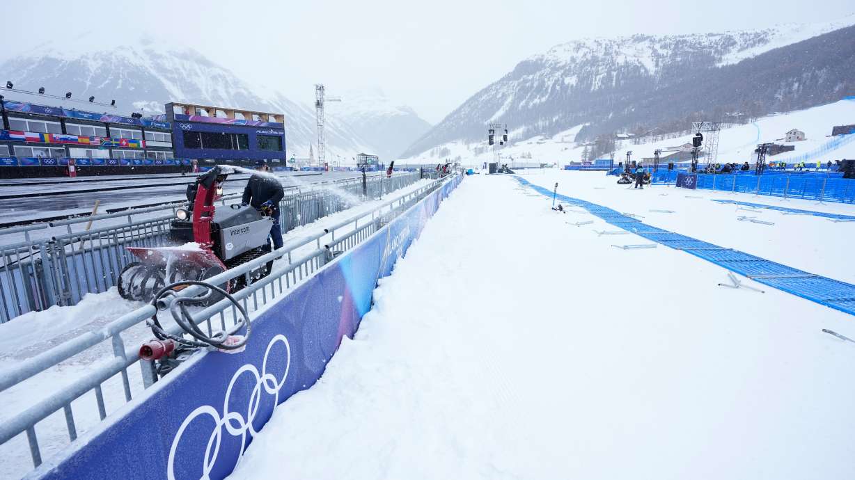 A worker blows snow off a path at the 2026 Winter Olympics, in Livigno, Italy, Wednesday. The IOC is open to earlier dates for future Games because of warmer temperatures.