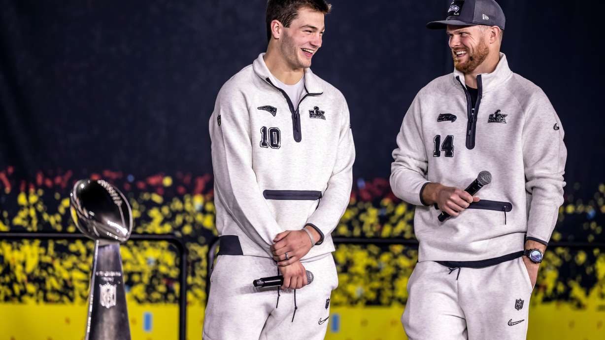 New Englad Patriots quarterback Drake Maye, left, and Seattle Seahawks quarterback Sam Darnold, right, smile on stage with the Lombardi Trophy during the NFL Super Bowl Opening Night, Monday, Feb. 2, 2026, in San Jose, Calif., ahead of the Super Bowl 60 football game between the New England Patriots and the Seattle Seahawks.