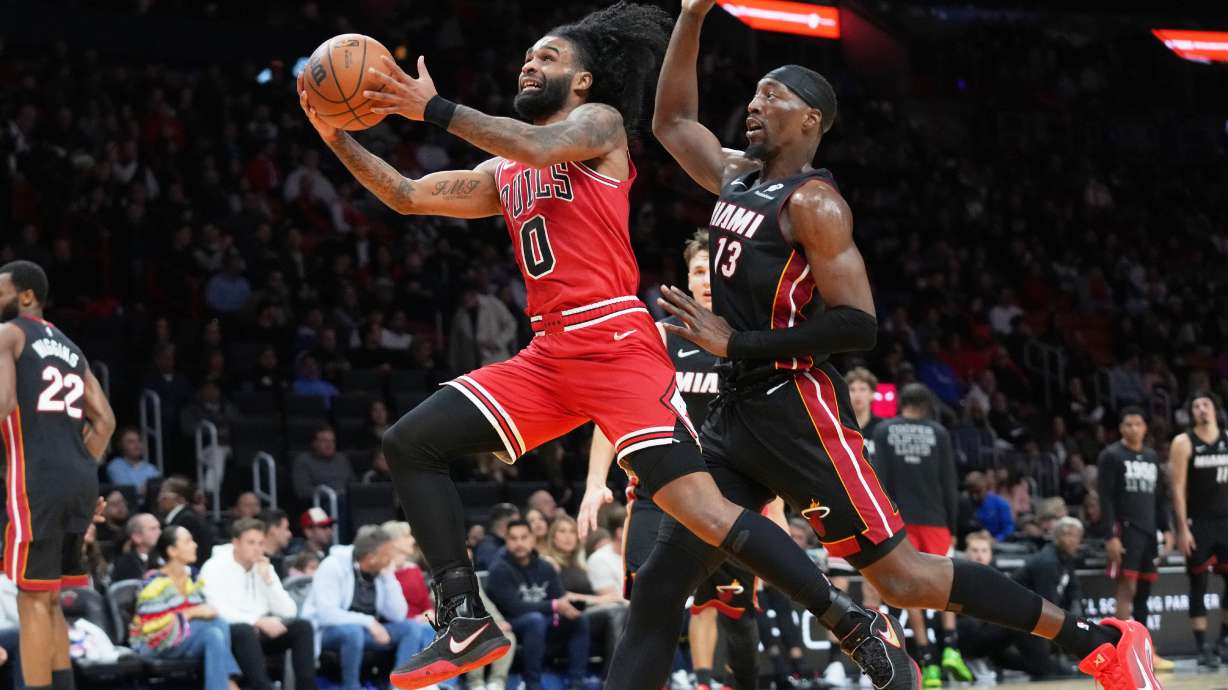 Chicago Bulls guard Coby White (0) drives to the basket as Miami Heat center Bam Adebayo (13) defends during the second half of an NBA basketball game, Sunday, Feb. 1, 2026, in Miami.