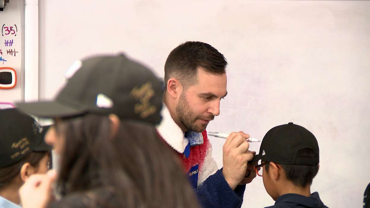 2018 Olympic medalist in luge, Chris Mazdzer, signs a fourth grader's hat at the Guadalupe Center in Salt Lake City, Friday. Mazdzer emphasized the journey to the Games starts in the classroom.