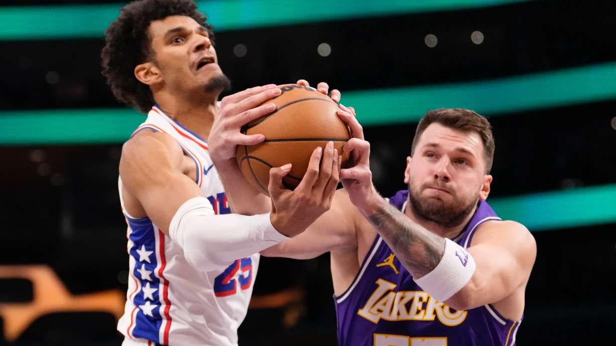 Philadelphia 76ers forward Dominick Barlow, left, and Los Angeles Lakers guard Luka Doncic reach for a rebound during the first half of an NBA basketball game Thursday, Feb. 5, 2026, in Los Angeles.