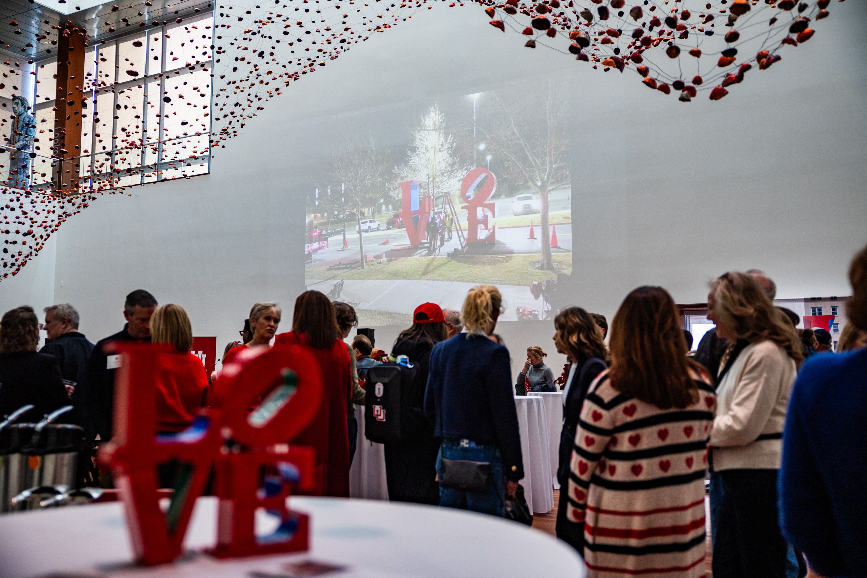 People involved in the installation of Robert Indiana's "LOVE" sculpture celebrate inside the Utah Museum of Fine Arts after viewing the sculpture on the south lawn in Salt Lake City on Saturday. University President Taylor Randall said he hopes it inspires positive change.