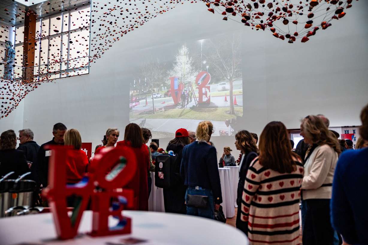 People involved in the installation of Robert Indiana's "LOVE" sculpture celebrate inside the Utah Museum of Fine Arts after viewing the sculpture on the south lawn in Salt Lake City on Saturday. University President Taylor Randall said he hopes it inspires positive change.