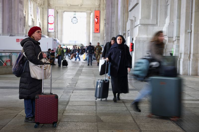 A woman looks at a board announcing delays at the Milan train station, as police investigate possible sabotage to electricity cables near the city of Bologna that have caused delays to a large part of the national railway network, in Milan, Saturday. 