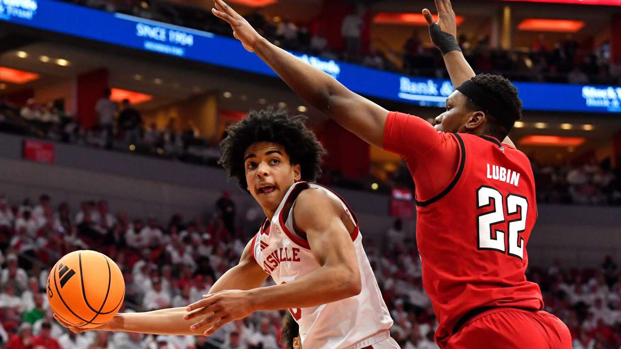 Louisville guard Mikel Brown Jr., left, passes the ball away from North Carolina State forward Ven-Allen Lubin (22) during the second half of an NCAA college basketball game in Louisville, Ky., Monday, Feb. 9, 2026.