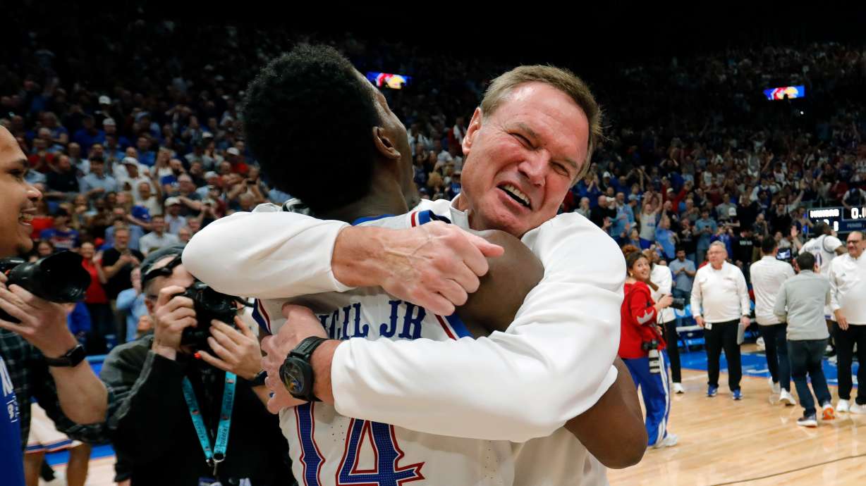 Kansas guard Melvin Council Jr. (14) is hugged by Kansas head coach Bill Self, right, as they celebrate after their team's upset over Arizona in an NCAA college basketball game, Monday, Feb. 9, 2026, in Lawrence, Kan.