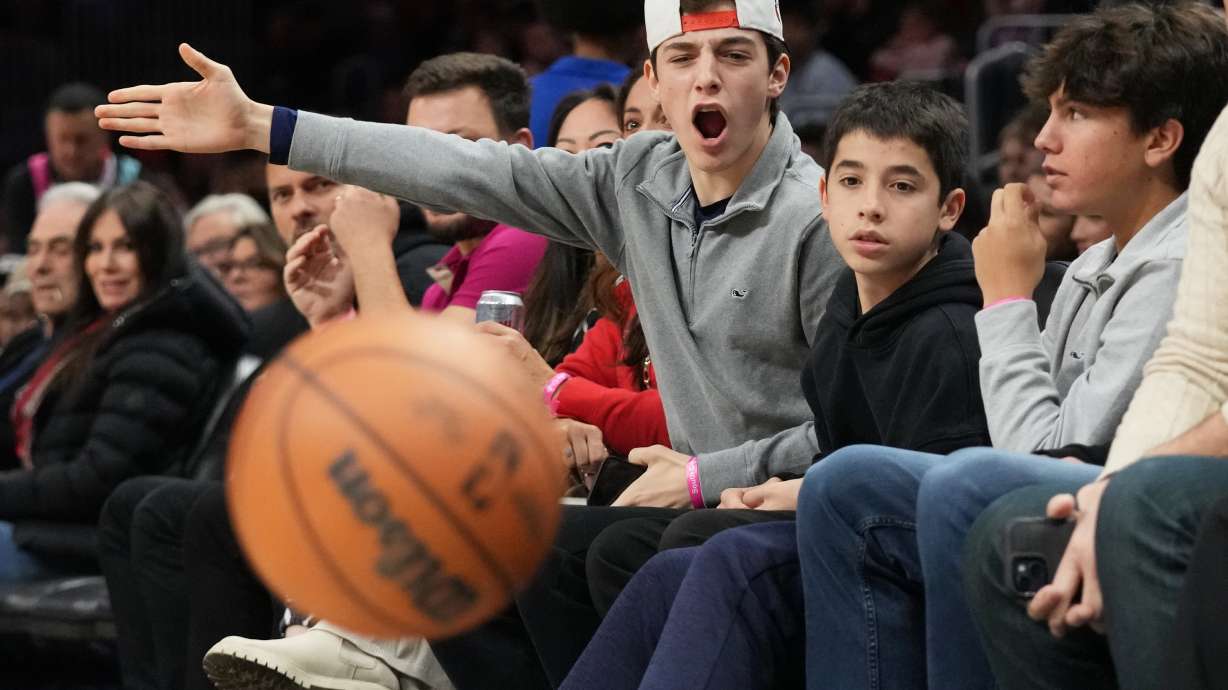 Lucas Gonzalez, 16, center, reacts to a play as he sits courtside with Matias Gonzalez, 13, second from right, and Sergio Masvidal, 15, right, during the first half of an NBA basketball game, Sunday, Feb. 1, 2026, in Miami.