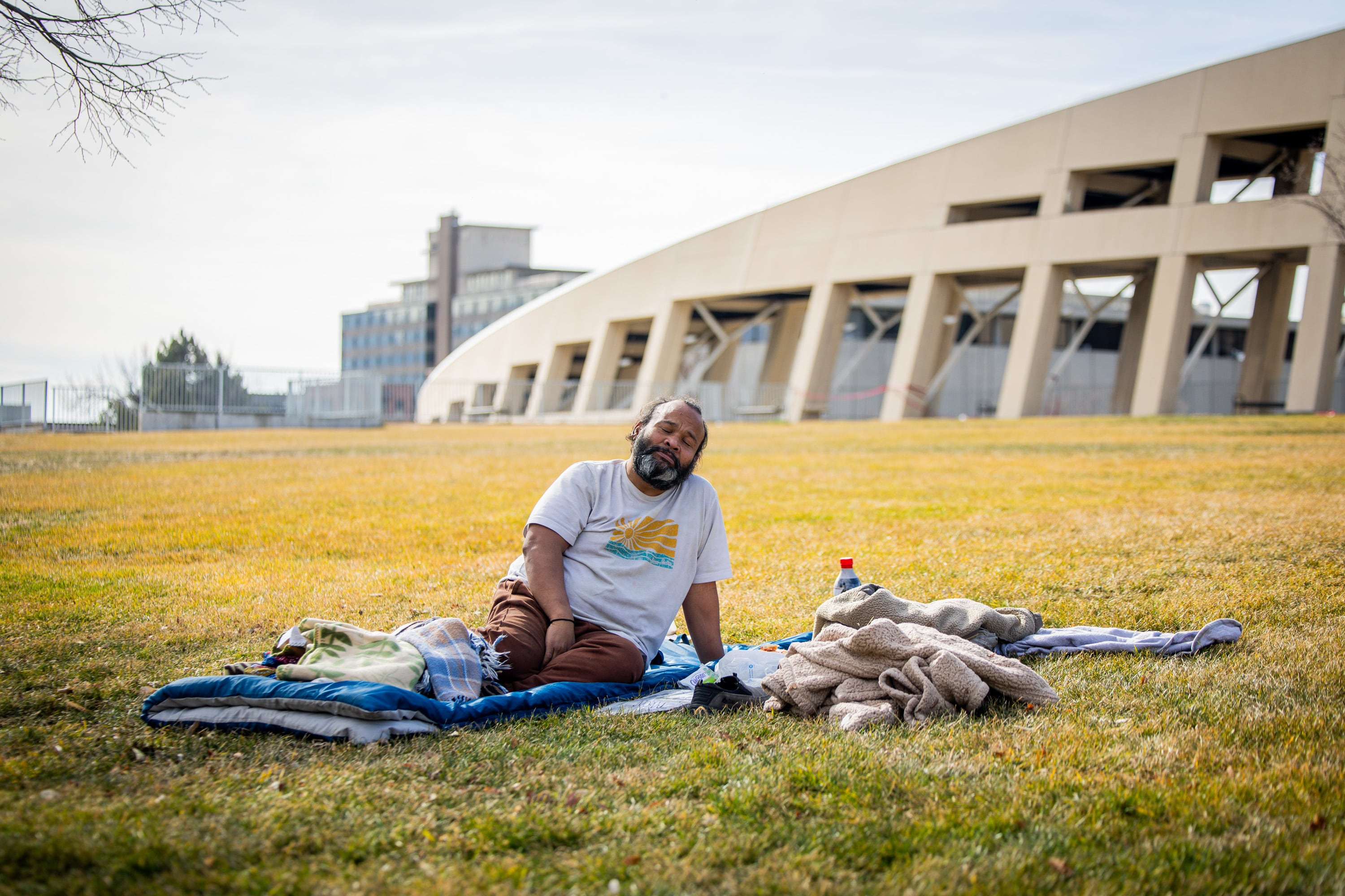 Jacob Myra Omar, a person experiencing homelessness, sits outside the Salt Lake City Public Library before going inside the library to take a nap in Salt Lake City on Feb. 3, 2026.