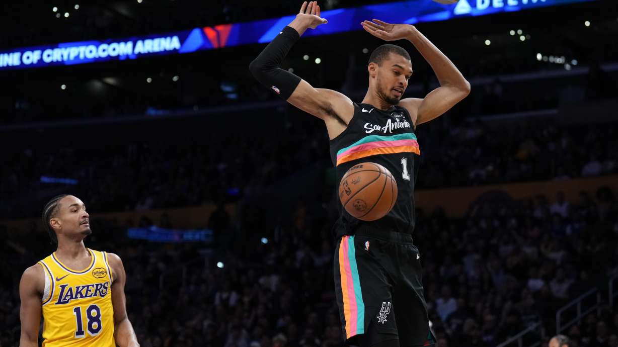 San Antonio Spurs forward Victor Wembanyama (1) descends after making a dunk as Los Angeles Lakers guard Kobe Bufkin (18) looks on during the first half of an NBA basketball game Tuesday, Feb. 10, 2026, in Los Angeles.