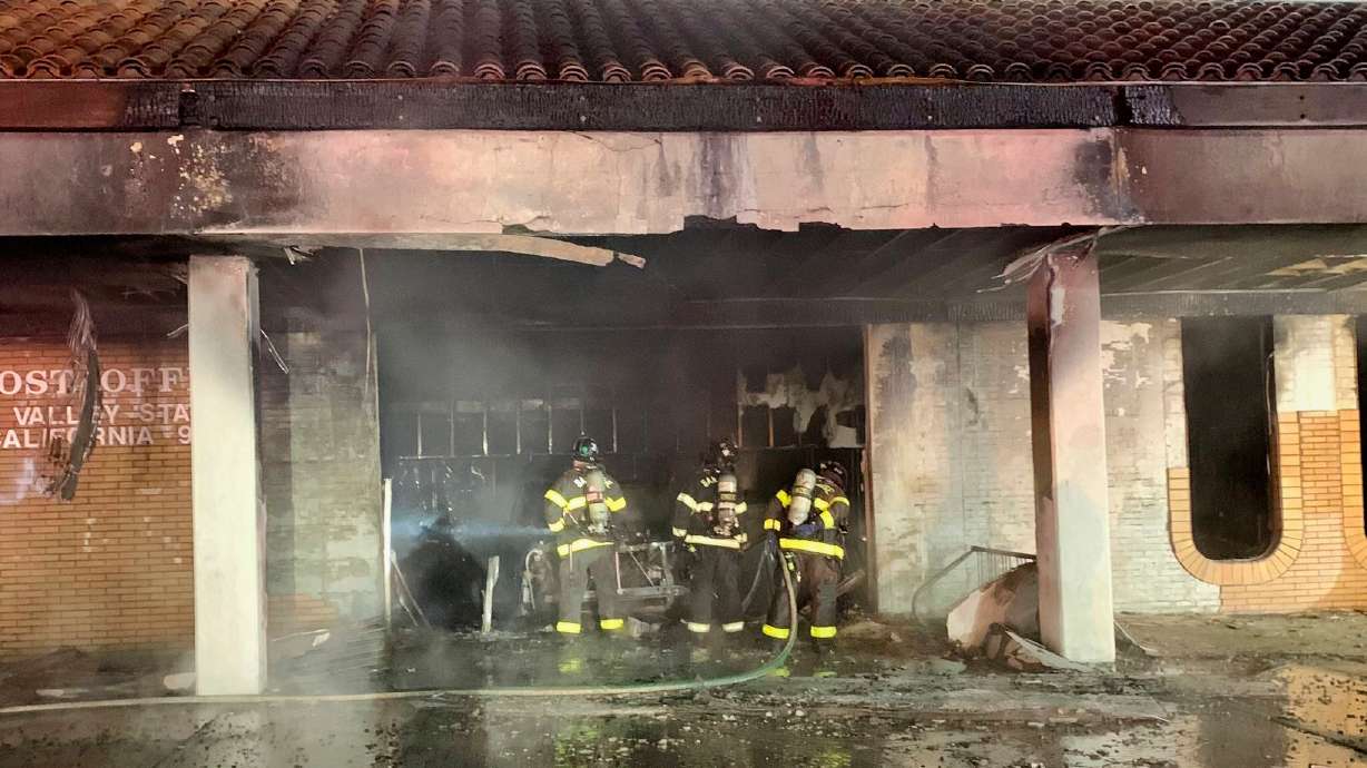 FILE - This photo provided by the San Jose Fire Department shows firefighters responding to a fire burning after a car crashed into a Post Office, early July 20, 2025, in San Jose, Calif.