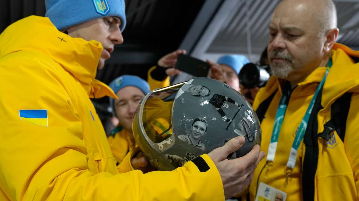 Ukrainian skeleton athlete Vladyslav Heraskevych left, holds his crash helmet at the mixed zone of the sliding center at the 2026 Winter Olympics, in Cortina d'Ampezzo, Italy, Thursday, Feb. 12, 2026.