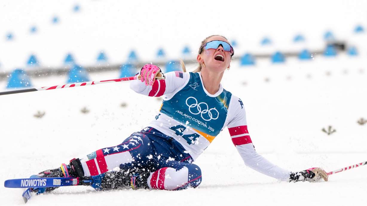 Jessie Diggins, of the United States, falls to the ground after crossing the finish line in the cross country skiing women's 10km interval start free at the 2026 Winter Olympics, in Tesero, Italy, Thursday, Feb. 12, 2026.