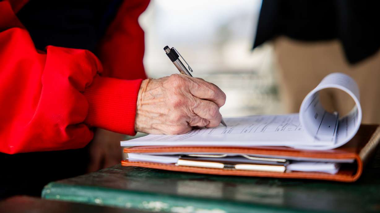 Geraldine Hooker, from Midvale, signs a petition to repeal Proposition 4 at a signature gathering event at Union Park in Midvale on Thursday. More than 2,000 Utah voters have asked to have their names removed from a petition to overturn Proposition 4.