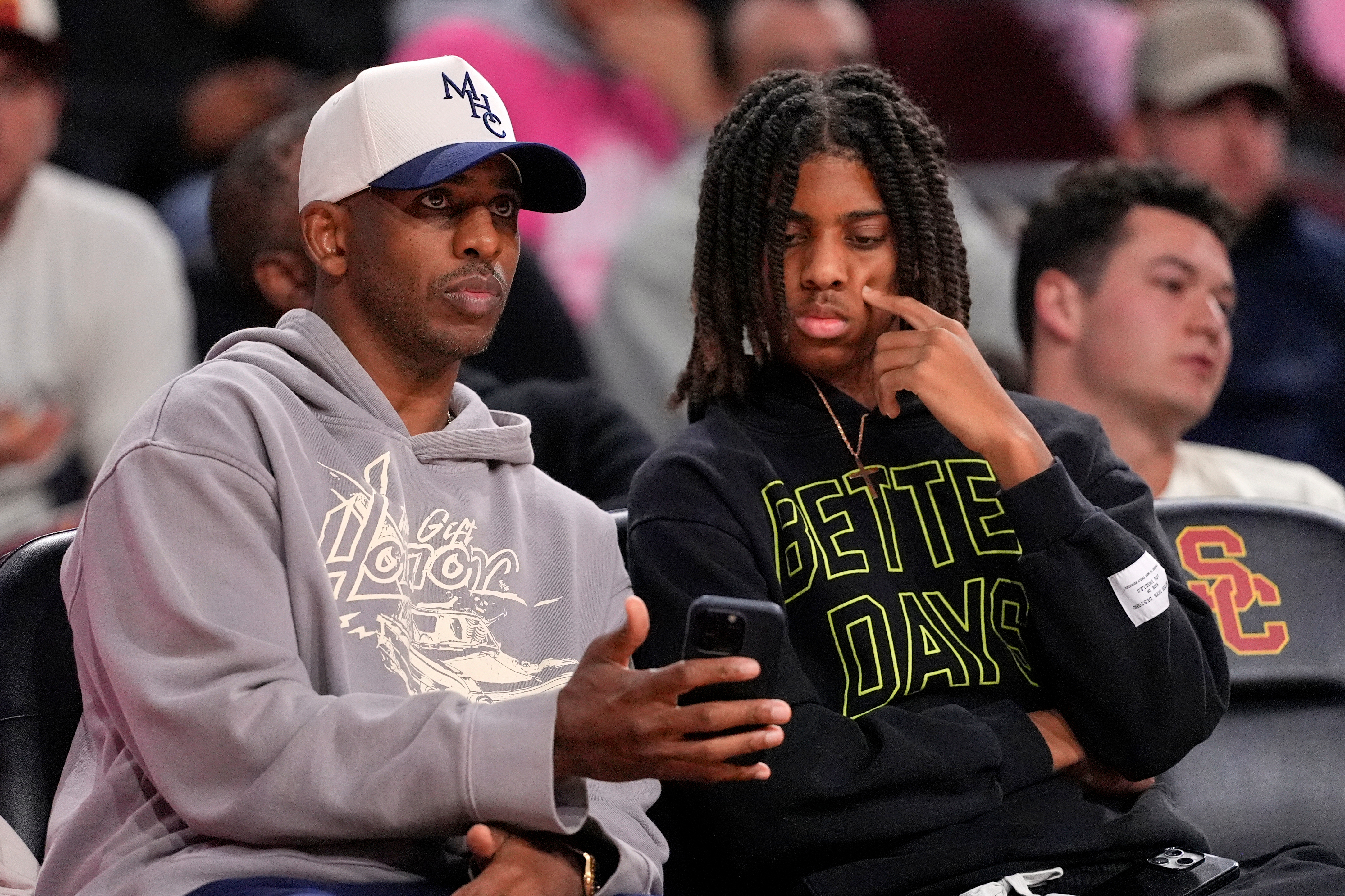 Basketball player Chris Paul, left, sits with his son Chris Paul Jr. during the second half of an NCAA college basketball game between Southern California and Northwestern, Wednesday, Jan. 21, 2026, in Los Angeles. 