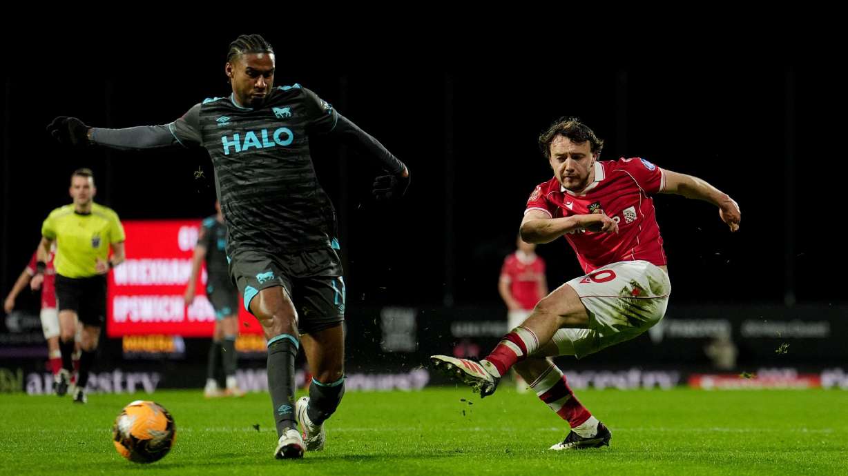 Wrexham's Ollie Rathbone, right, has a shot at goal against Ipswich Town during an English FA Cup fourth round soccer, Friday, Feb. 13, 2026, in Wrexham, Wales.