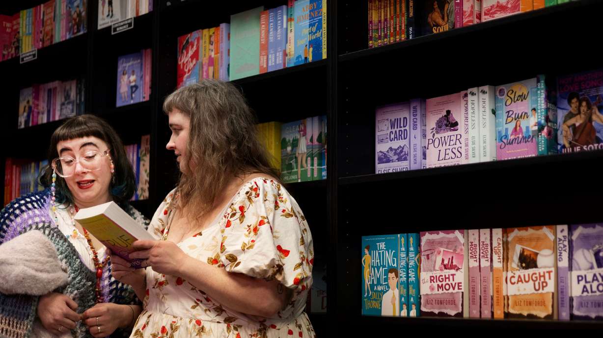 Astra Hess, left, and her wife Cassi Hess, of Ogden, read the back cover of a book at the Romantics Archive in Ogden on Wednesday.