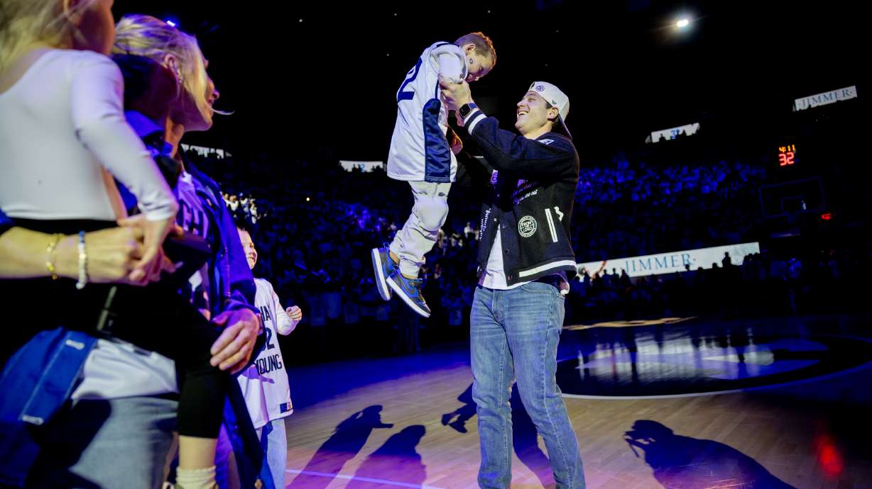 BYU’s Jimmer Fredette lifts his son in the air after his No. 32 jersey is retired and hung in the rafters during a halftime ceremony during a game against the Colorado Buffaloes at the Marriott Center in Provo on Saturday, Feb. 14, 2026.