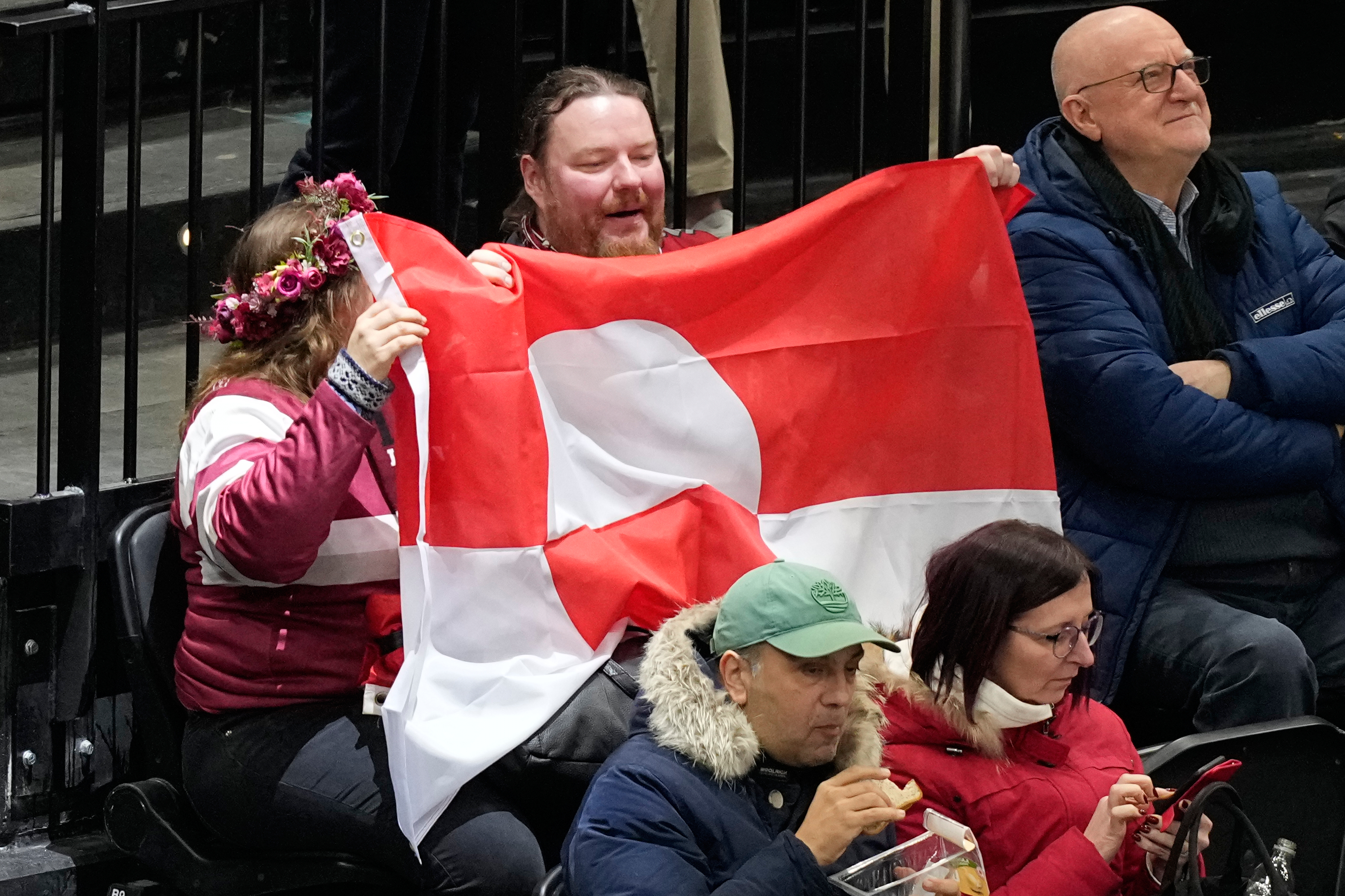 Fans hold Greenland national flag before a preliminary round match of men's ice hockey between United States and Denmark at the 2026 Winter Olympics, in Milan, Italy, Saturday, Feb. 14, 2026. 