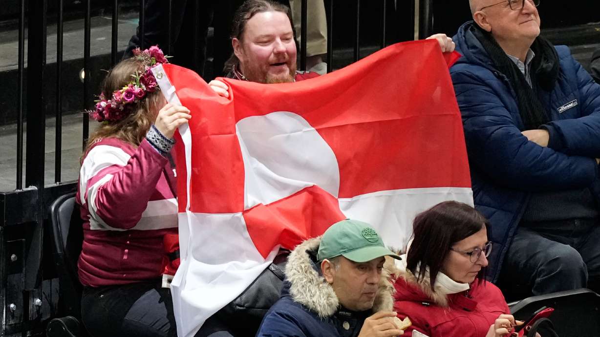 Fans hold Greenland national flag before a preliminary round match of men's ice hockey between United States and Denmark at the 2026 Winter Olympics, in Milan, Italy, Saturday, Feb. 14, 2026.