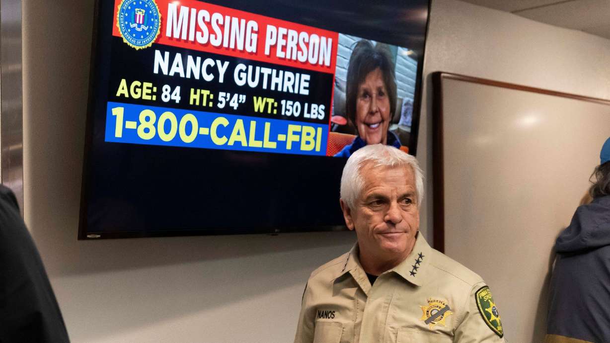 Pima County Sheriff Chris Nanos exits past a missing persons poster in Tucson, Ariz., on Feb. 5. The search for Guthrie stretched into a third week on Wednesday.