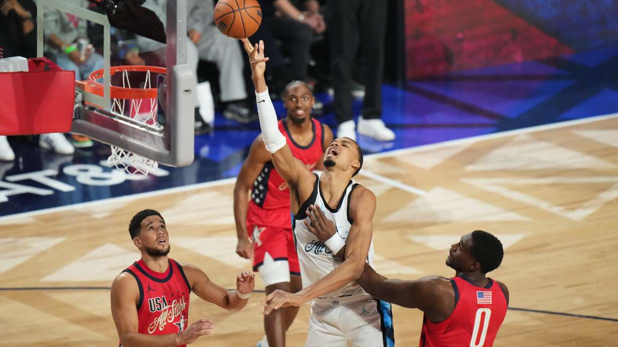 World center Victor Wembanyama, of France, shoots over USA Stars guard Devin Booker, left, and forward Jalen Duren during the NBA All-Star basketball game Sunday, Feb. 15, 2026, in Inglewood, Calif.
