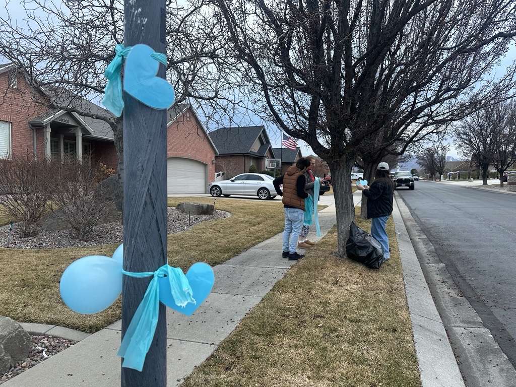 Neighbors tie blue ribbons around trees to show their support for the grieving family of Addi Smith, Monday. Addi was killed in a murder-suicide in Las Vegas, according to police.