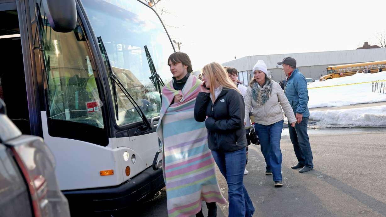 High school hockey students walk onto a public transit bus near the Lynch Arena in Pawtucket, R.I., after a shooting at the ice rink, Monday.