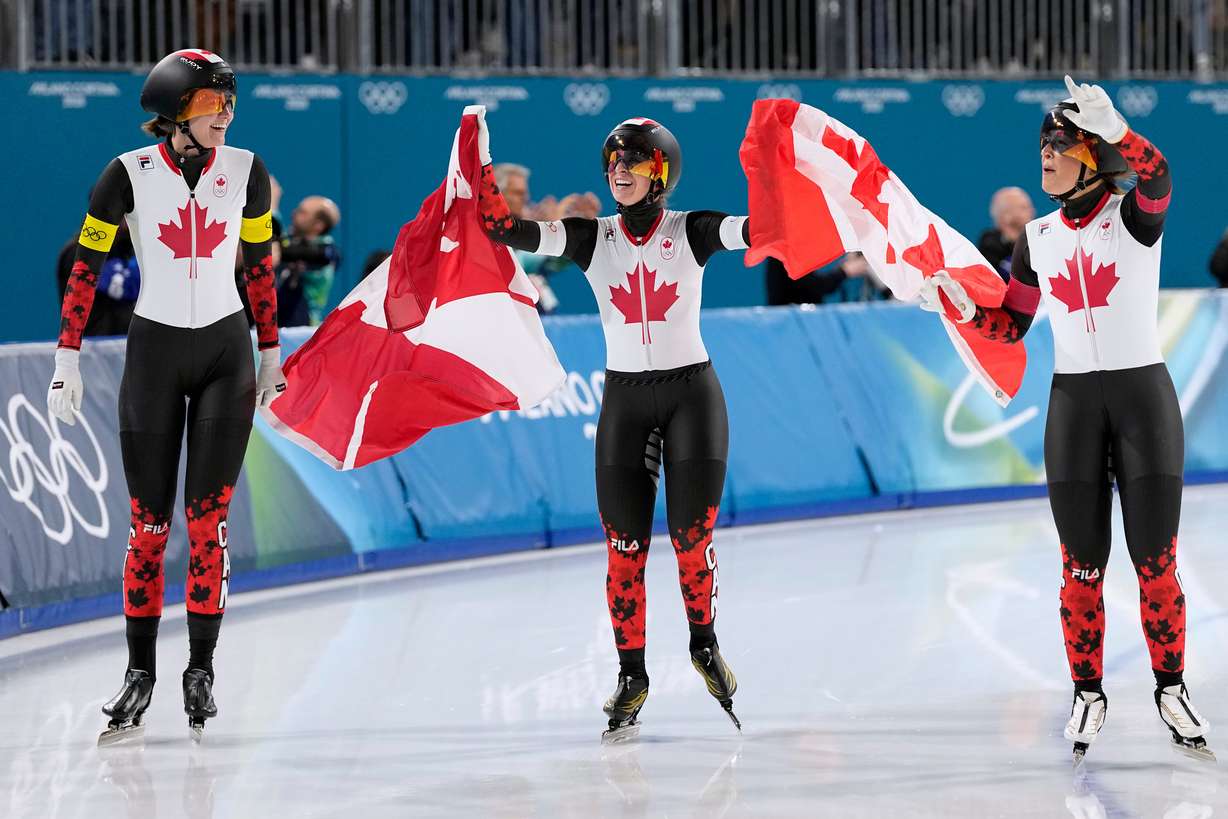 Team Canada with Ivanie Blondin, center and white armband, Valerie Maltais, right and red armband, and Isabelle Weidemann, left and yellow armband, celebrate winning the gold medal in the final of the women's team pursuit speedskating race at the 2026 Winter Olympics, in Milan, Italy, Tuesday, Feb. 17, 2026.