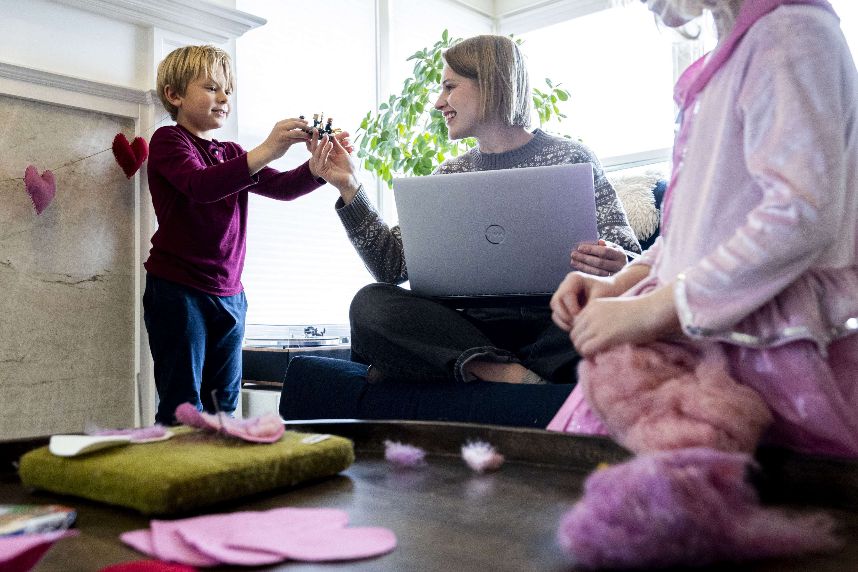 Rhiannon McDaniel checks out a Lego creation created by her son, Atticus, 7, as her daughter, Brita, 4, works on felting a heart at her family’s home in Holladay on Wednesday. McDaniel used to work full time with a salary, but over the summer switched to part time with hourly pay to stay home and save on child care costs.