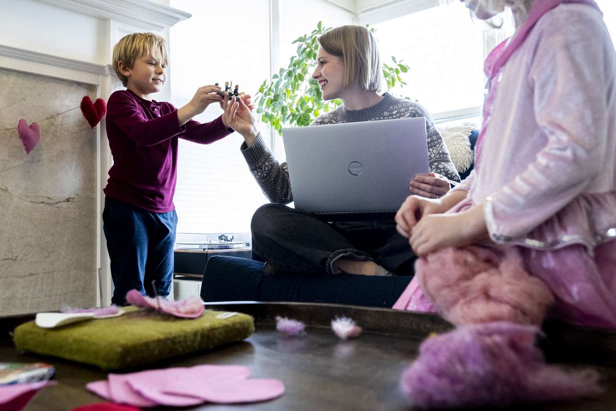Rhiannon McDaniel checks out a Lego creation created by her son, Atticus, 7, as her daughter, Brita, 4, works on felting a heart at her family’s home in Holladay on Wednesday. McDaniel used to work full time with a salary, but over the summer switched to part time with hourly pay to stay home and save on child care costs.