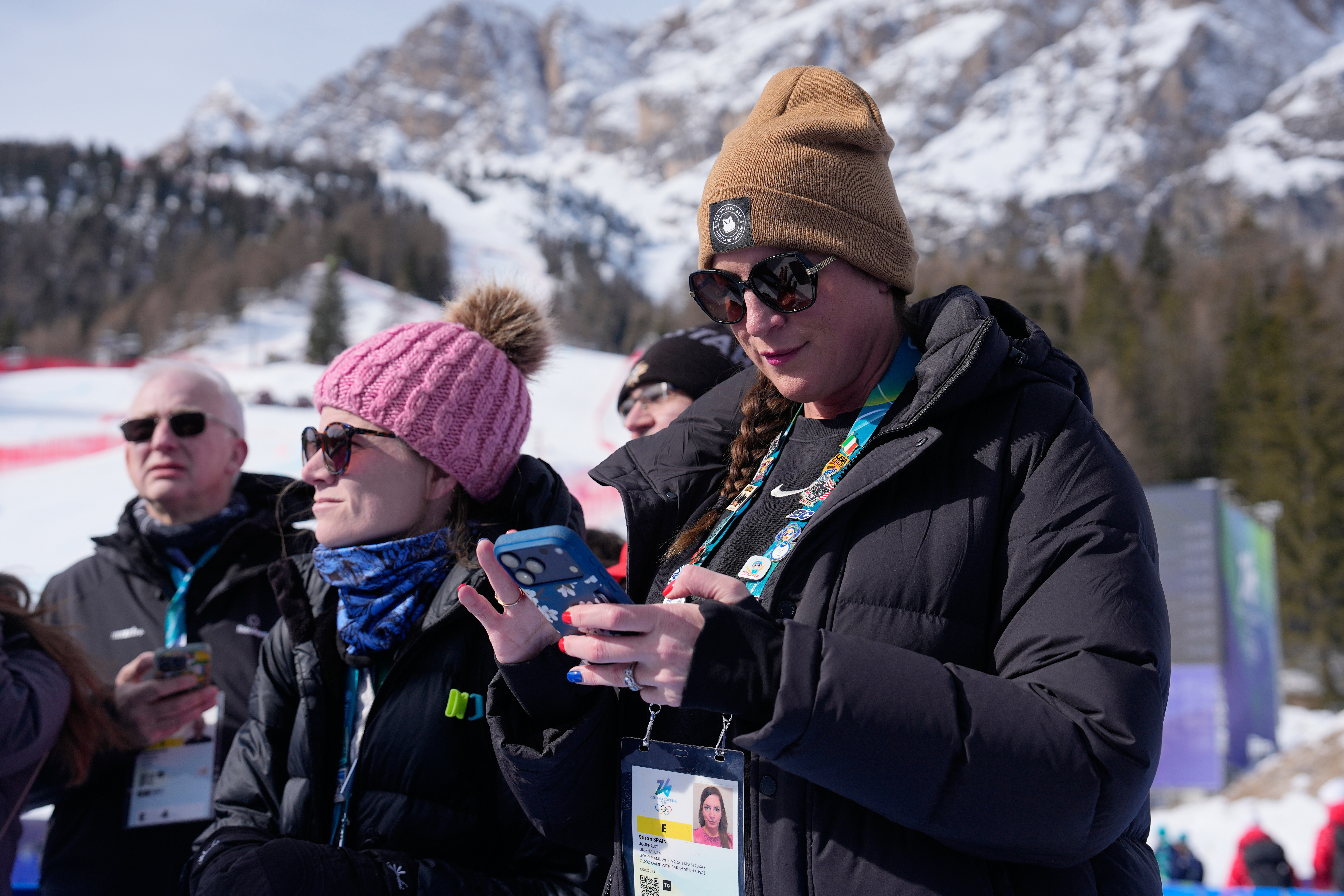 ESPN reporters Sarah Spain, right, and Alex Azzi wait to interview the athletes after the first run of an alpine ski women's giant slalom race at the 2026 Winter Olympics in Cortina d'Ampezzo, Italy, Sunday, Feb. 15, 2026. 