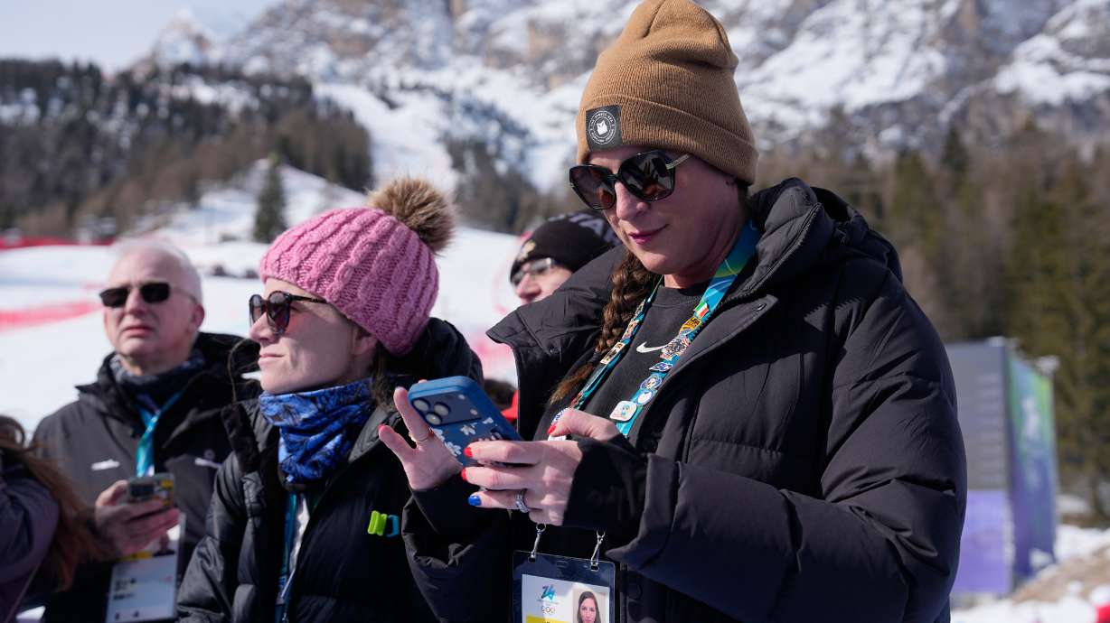 ESPN reporters Sarah Spain, right, and Alex Azzi wait to interview the athletes after the first run of an alpine ski women's giant slalom race at the 2026 Winter Olympics in Cortina d'Ampezzo, Italy, Sunday, Feb. 15, 2026.