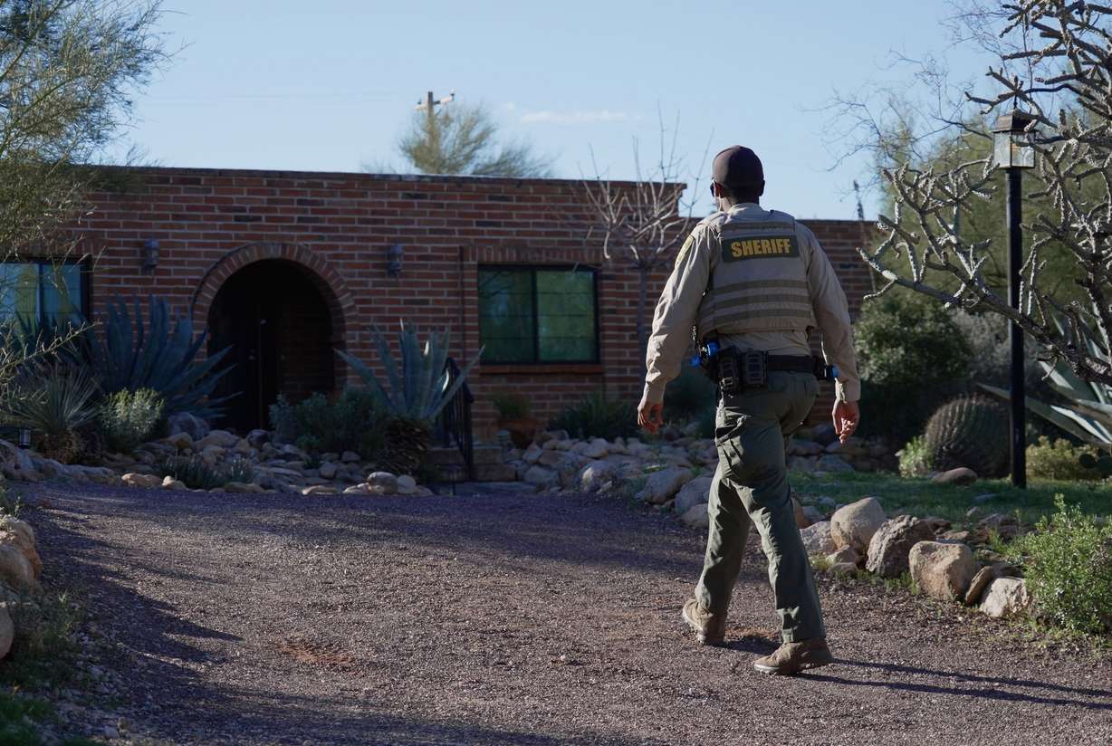 A member of the Pima County Sheriff's Office remains outside Nancy Guthrie's home on Monday in Tucson, Ariz. The search for the 84-year-old has stretched into its third week.