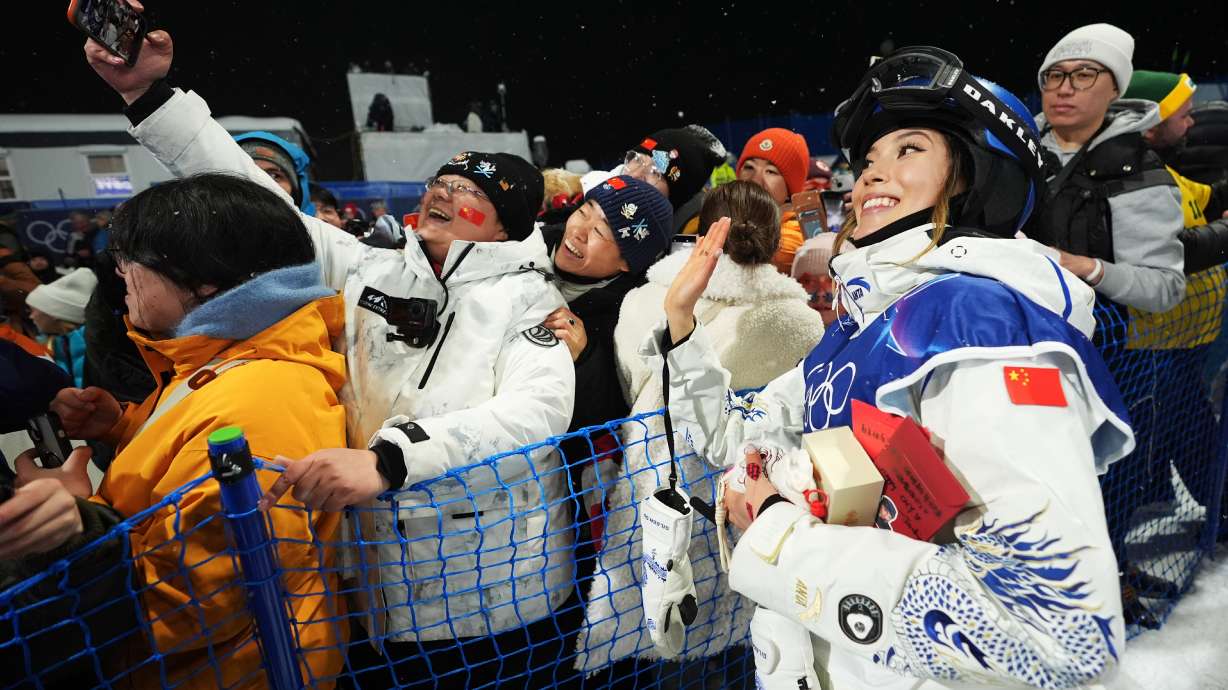 China's Eileen Gu takes photos with attendees after the women's freestyle skiing halfpipe qualifications at the 2026 Winter Olympics, in Livigno, Italy, Thursday, Feb. 19, 2026.