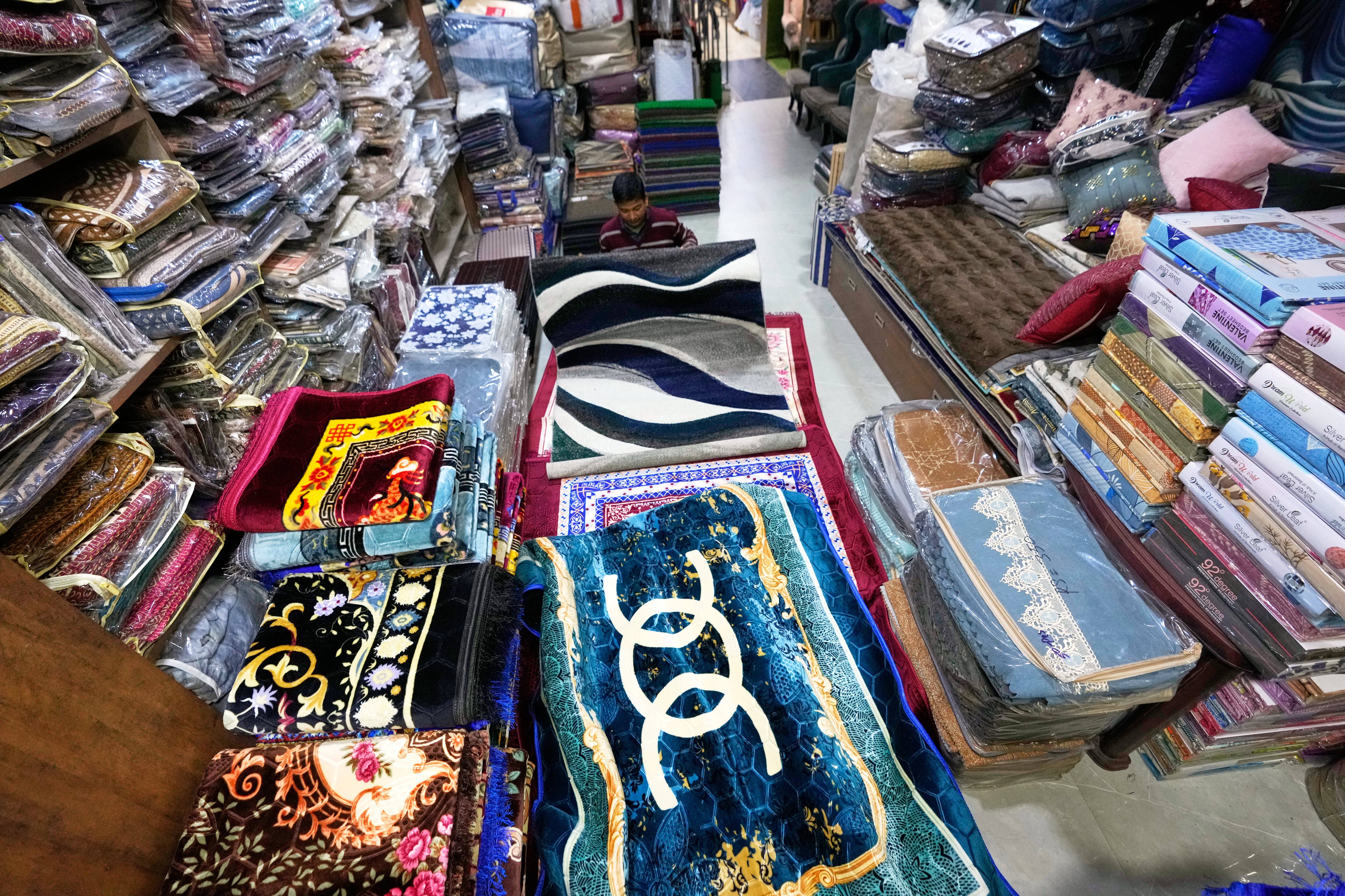 A salesman shows carpets in a showroom in Guwahati, India, Tuesday, Feb. 3, 2026.