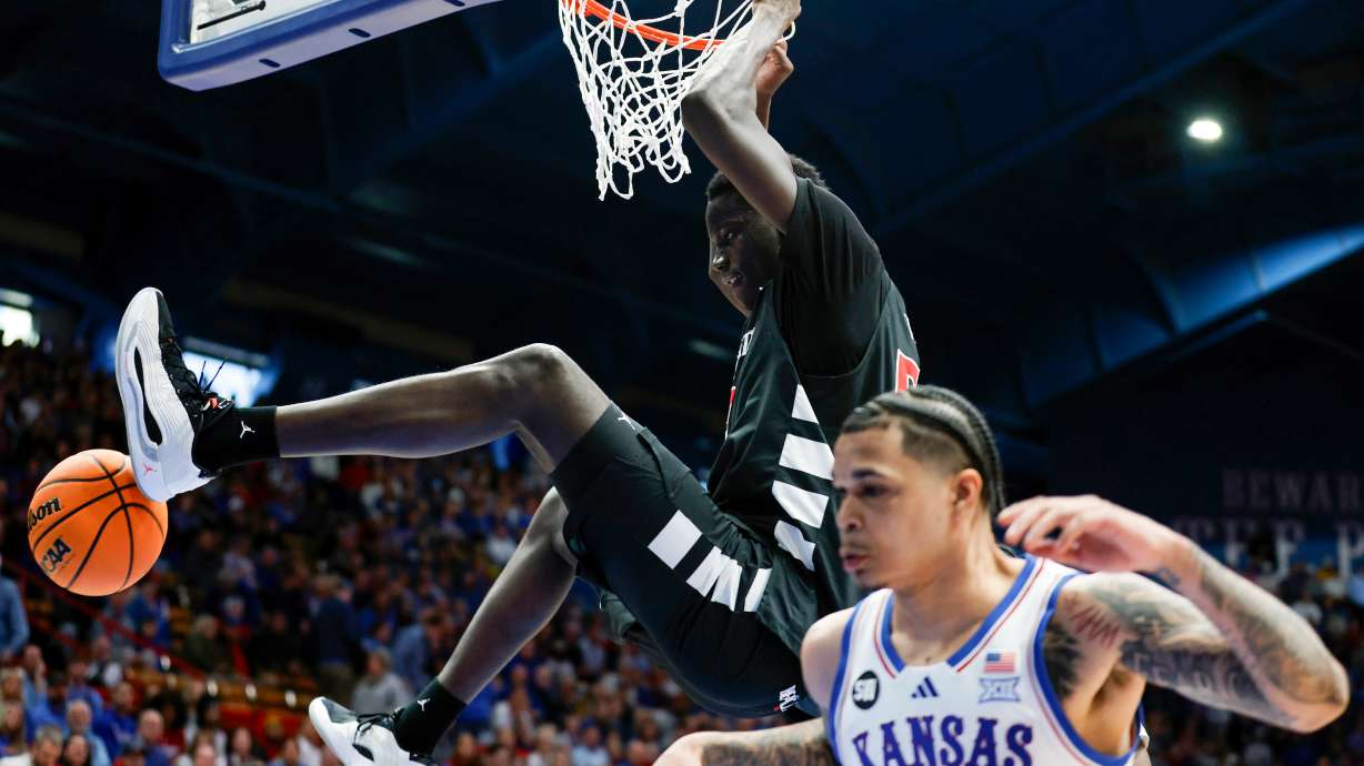 Cincinnati center Moustapha Thiam, top, dunks over Kansas guard Jayden Dawson (1) during the second half of an NCAA college basketball game, Saturday, Feb. 21, 2026, in Lawrence, Kan.