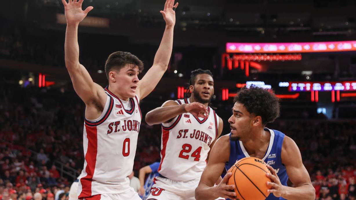 Creighton guard Nik Graves is defended by St. John's guard Dylan Darling (0) and forward Zuby Ejiofor (24) during the first half of an NCAA college basketball game, Saturday, Feb. 21, 2026, in New York.