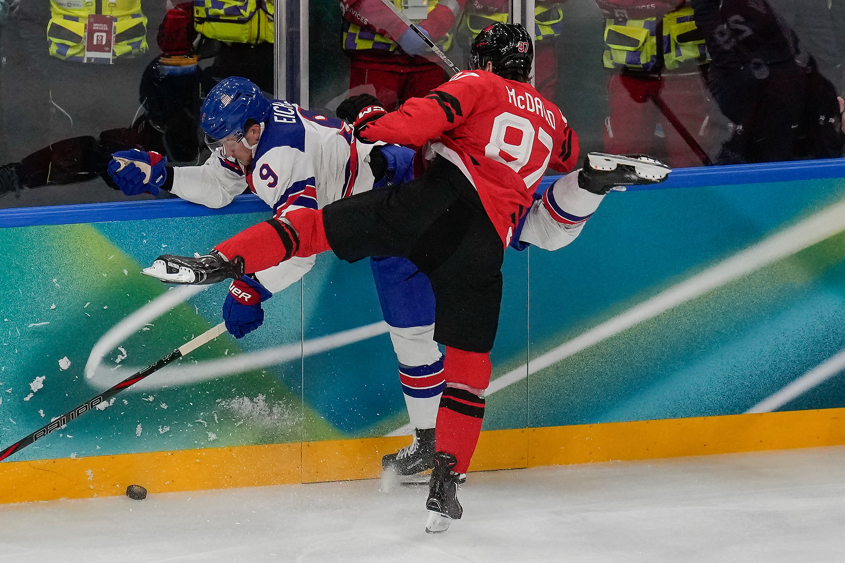 Canada's Connor McDavid (97) checks United States' Jack Eichel (9) into the wall during the first period of the men's ice hockey gold medal game at the 2026 Winter Olympics, in Milan, Italy, Sunday.
