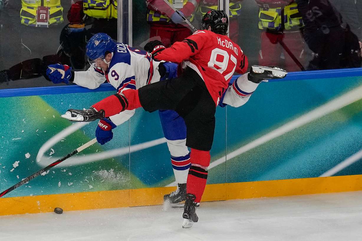 Canada's Connor McDavid (97) checks United States' Jack Eichel (9) into the wall during the first period of the men's ice hockey gold medal game at the 2026 Winter Olympics, in Milan, Italy, Sunday.