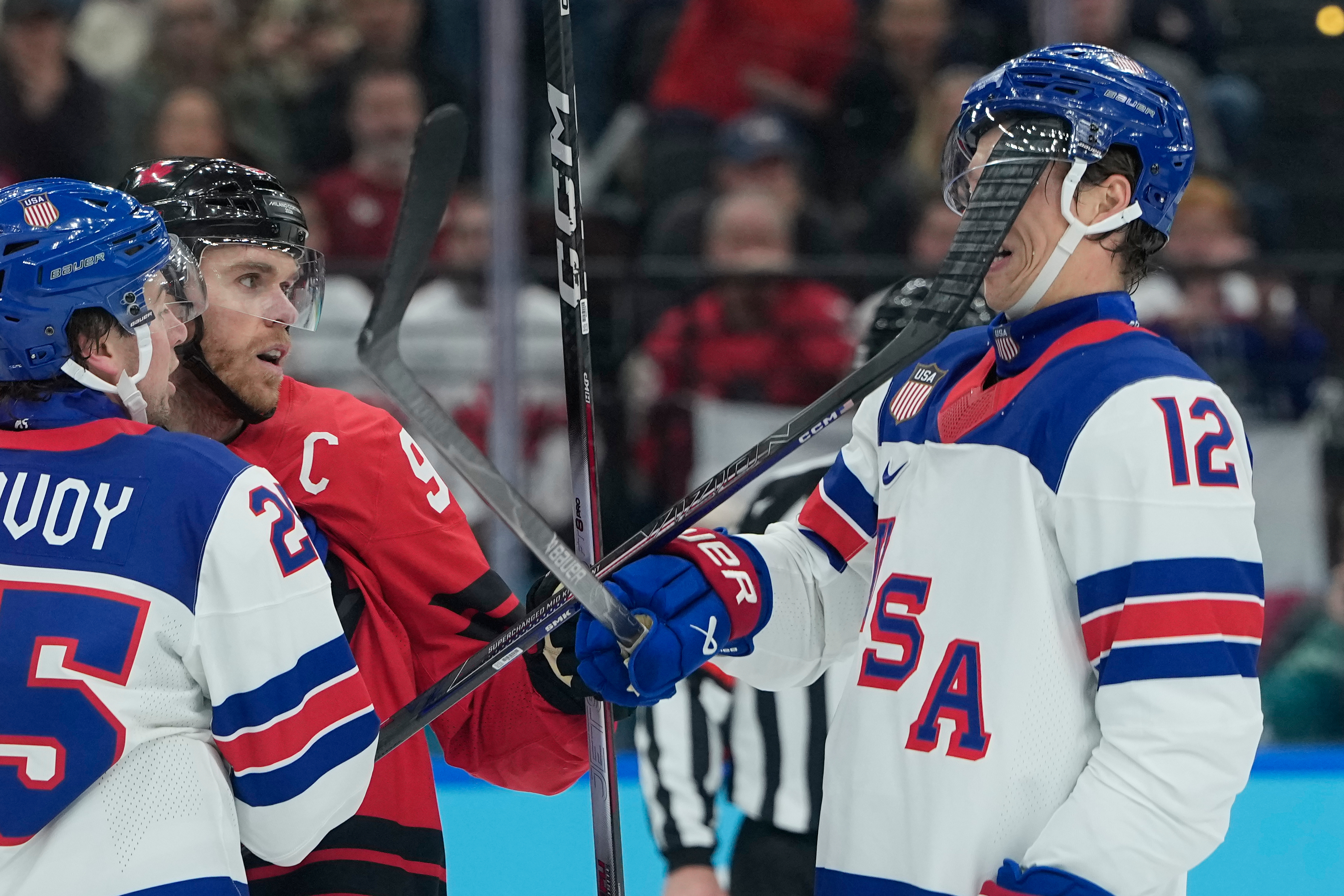 United States' Matt Boldy (12) is hit in the face by the stick of Canada's Connor McDavid (97) during the first period of a men's ice hockey gold medal game between Canada and the United States at the 2026 Winter Olympics, in Milan, Italy, Sunday.