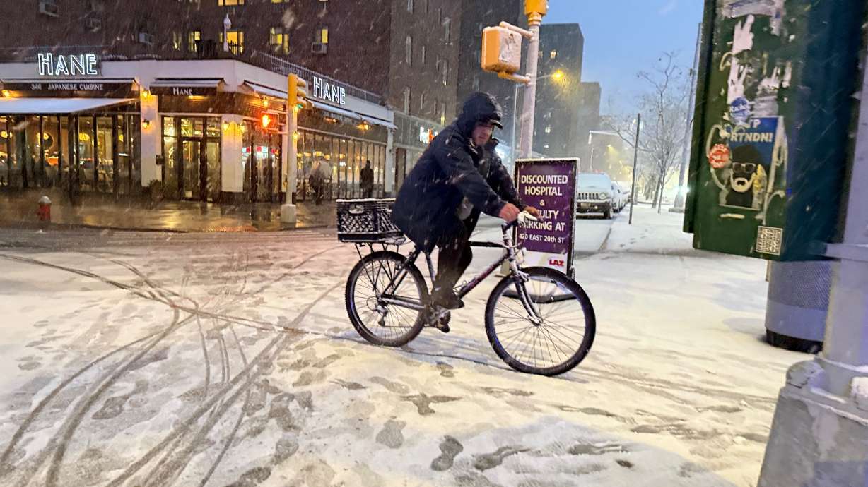 A man rides a bicycle in the beginning of an intense snowstorm by 20th Street and First Avenue, Sunday, in New York.